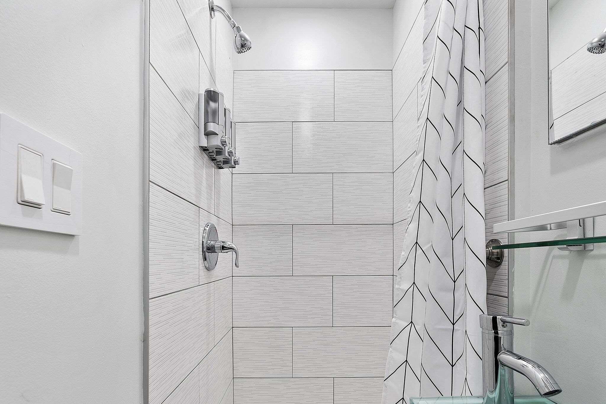 A modern bathroom with a shower, a glass sink, and a towel rack.