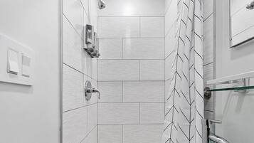 A modern bathroom with a shower, a glass sink, and a towel rack.