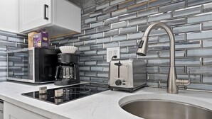 A modern kitchen with a stainless steel sink, a coffee maker, a toaster, and a microwave. - Ututu Stay West (Philadelphia)
