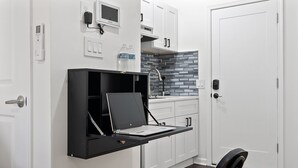 A compact kitchen with white cabinets, a black countertop, and a built-in stove. - Ututu Stay West (Philadelphia)