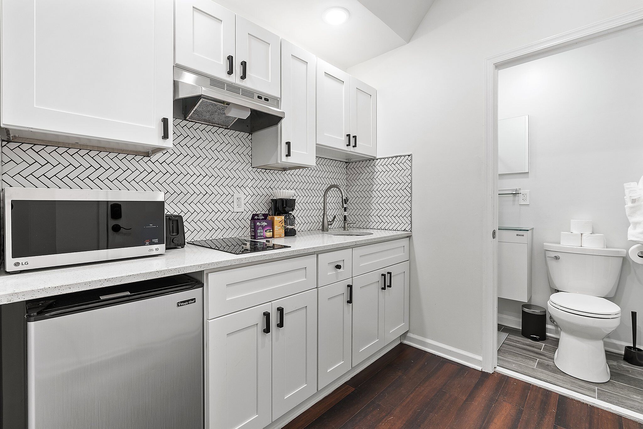 A modern kitchen with white cabinets, a microwave, and a dishwasher.