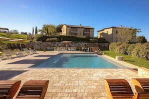Una piscina con lettini da relax e un muro in pietra.