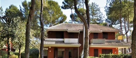 A two-story building with a tiled roof, surrounded by trees and a well-maintained lawn.