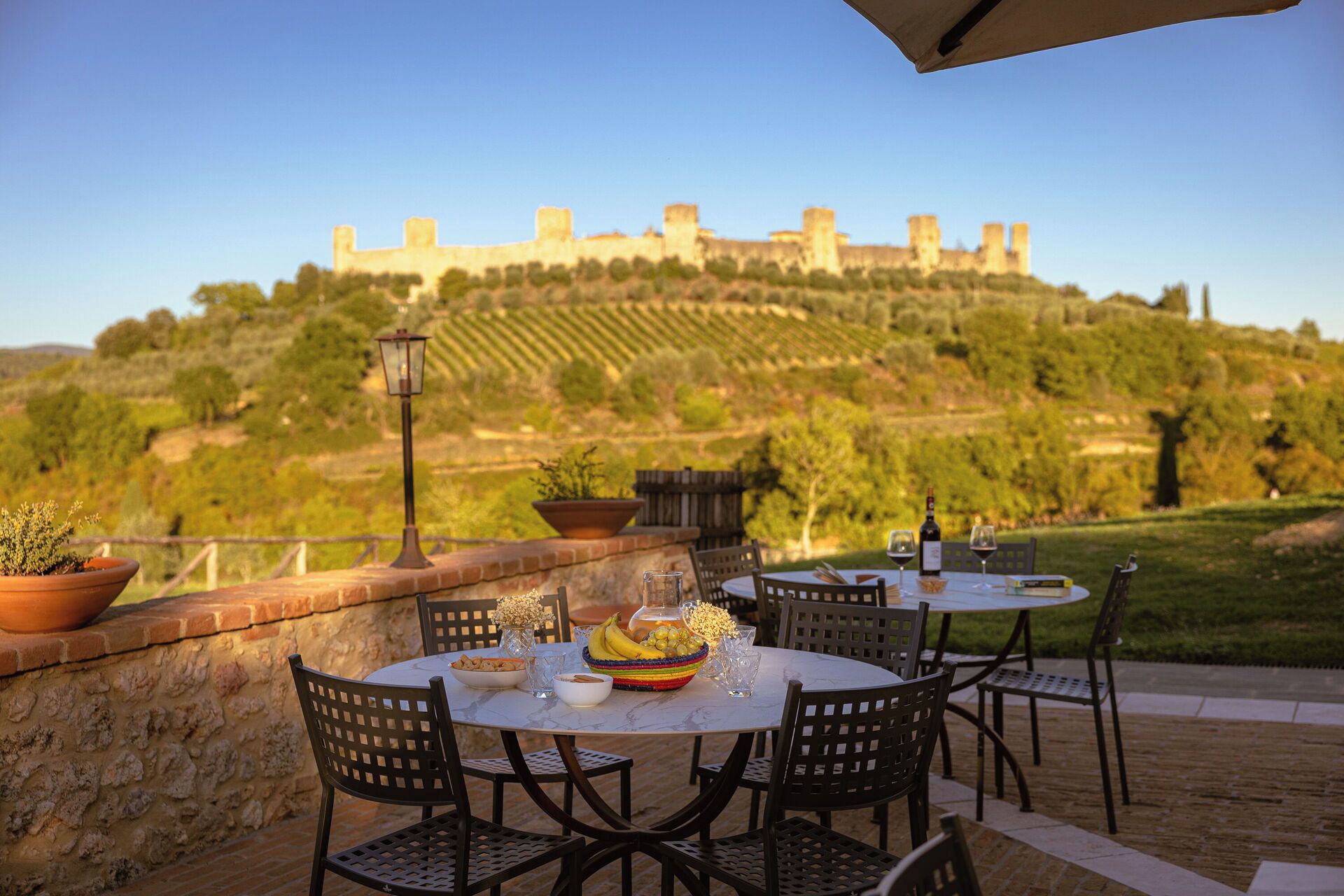 Zona pranzo all'aperto con tavolo apparecchiato per due, con vista su un castello storico su una collina.