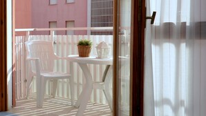 A balcony with white chairs and a small table, a wicker basket, and a decorative item. - Delightful studio in the town center (Bibione)