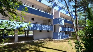 A modern building with a blue and white color scheme, featuring a courtyard with trees and a clear sky.