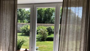 A view through a glass door with a garden outside. - Bedroom 1 - La Rêveuse (PEUPLINGUES)