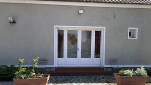 A house with a double door, a small window, and two potted plants on a stone pathway. - Bedroom 1 - La Rêveuse (PEUPLINGUES)