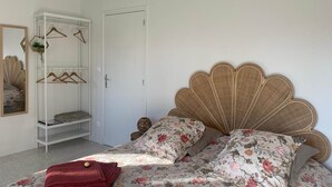 A bedroom with a bed featuring a scalloped headboard, a white wardrobe with shelves, and a mirror on the wall. - Bedroom 1 - La Rêveuse (PEUPLINGUES)
