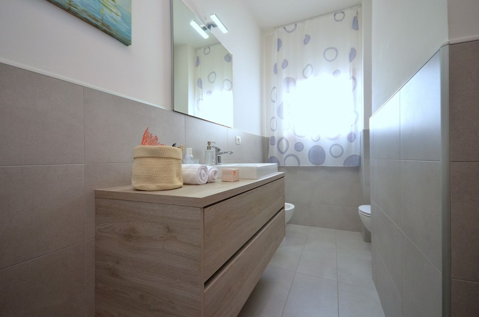 A modern bathroom with a wooden vanity, a large mirror, and a shower area.