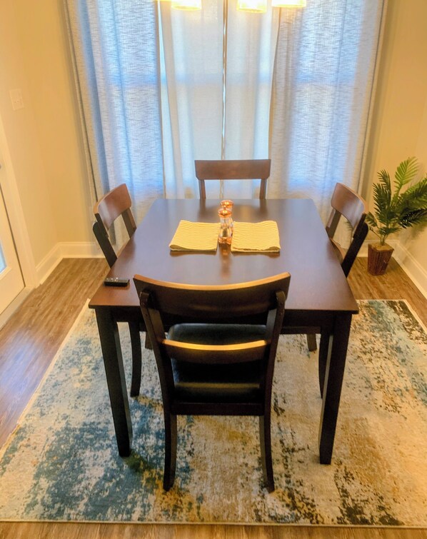 Une table à manger avec quatre chaises, un salier et un poivrier, et une serviette pliée au centre de la table.