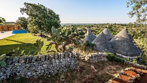 Un muro de piedra, un cactus y una construcción de piedra en un jardín.