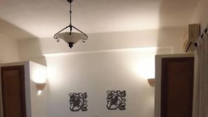 A bedroom with a bed, bedside tables, a ceiling light, and decorative wall art. - Black Beach Village (Santorini)