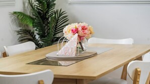 A dining table with a vase of flowers, a decorative item, and a clear glass.