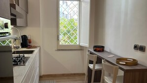 A compact kitchen with a window, a dining area with a table and chairs, and a built-in stove. - Casa Degli Aranci Charming apartment in the prestigious neighborhood of Vomero (Napoli)
