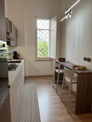 A compact kitchen with a window, a dining area with a table and chairs, and a built-in stove. - Casa Degli Aranci Charming apartment in the prestigious neighborhood of Vomero (Napoli)