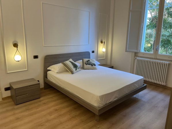 A modern bedroom with a wooden bed, white walls, and two bedside tables.