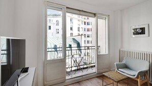 Eine moderne Wohnung mit Balkon, Fernseher, Sofa und Heizkörper.