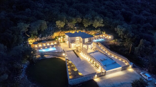 A multi-story building with a swimming pool, outdoor seating, and a stone pathway.