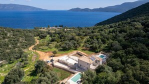 A coastal property with a swimming pool, a large building, and a dirt road leading to it.