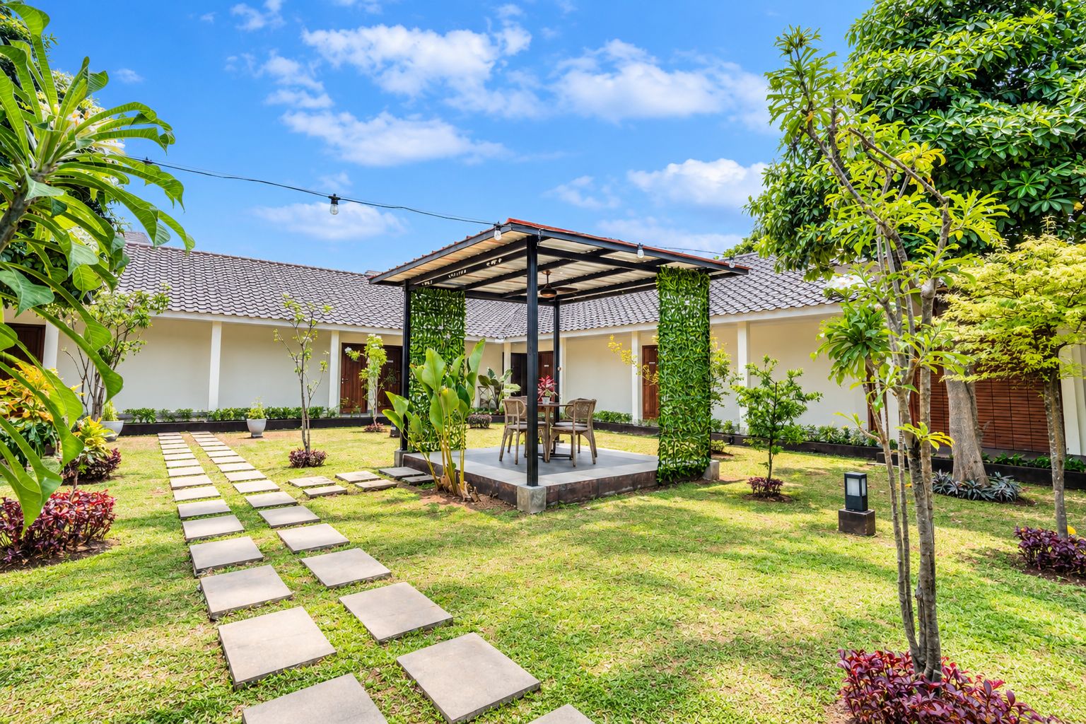 A covered outdoor seating area with a pergola, surrounded by a well-maintained garden with stepping stones and various plants.