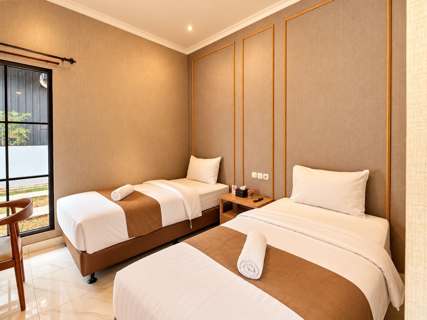 Habitación de hotel con dos camas, una mesita y una ventana.