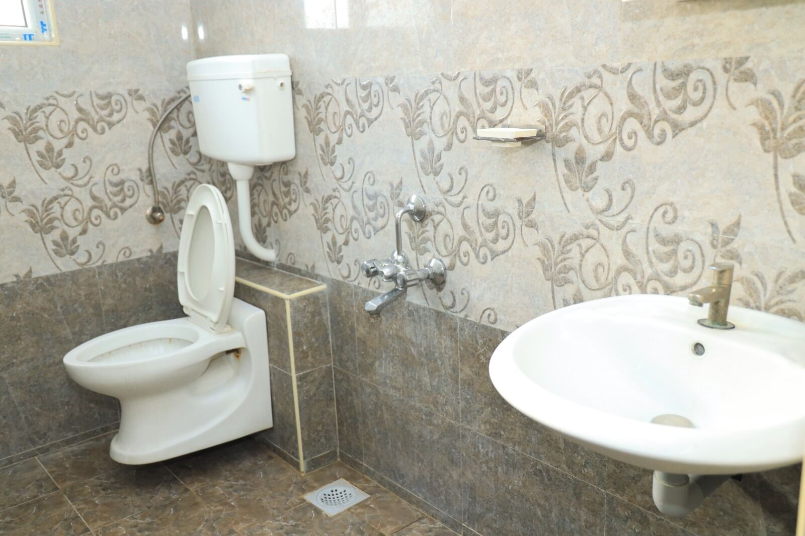 Een badkamer met toilet, wastafel en decoratieve wandtegels.