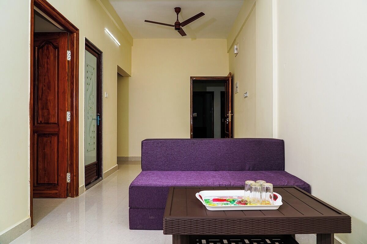 A hallway with a purple sofa, a table with a tray of food, and a ceiling fan.