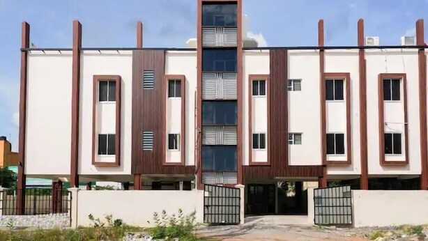 A modern multi-story building with a symmetrical facade, featuring vertical wooden accents and large windows. - AK Vellore Stays  (Vellore)