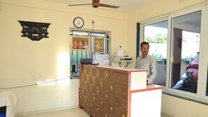 A reception area with a patterned counter, a clock, and a window with a view of the outside. - AK Vellore Stays  (Vellore)
