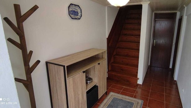 A hallway with a wooden staircase, a small wooden cabinet, and a tiled floor. - Pretty town house located next to the medieval town of Penela and its castle.  (Penela)