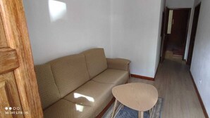 A hallway with a beige sofa and a small round table. - Pretty town house located next to the medieval town of Penela and its castle.  (Penela)