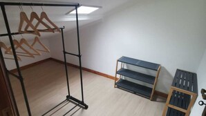 A room with a black metal rack with wooden hangers, a wooden shelf unit with three shelves, and a small wooden cabinet with a metal handle. - Pretty town house located next to the medieval town of Penela and its castle.  (Penela)