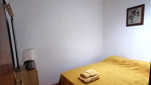 A room with a bed, a wooden cabinet, a lamp, and a framed picture on the wall. - Pretty town house located next to the medieval town of Penela and its castle.  (Penela)