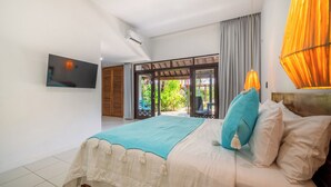 A bedroom with a bed, a TV mounted on the wall, and a view of the outdoors through a sliding door.