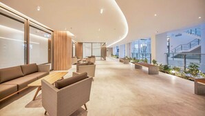 A spacious lobby with a curved ceiling, a seating area with sofas and chairs, and a view of the building's exterior through large windows. - Luxury Apartment in Phu My Hung (Ho Chi Minh City)