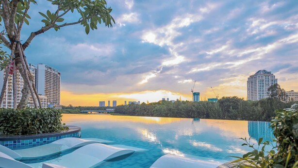 A swimming pool with tiered steps, surrounded by greenery and overlooking a cityscape with high-rise buildings. - Luxury Apartment in Phu My Hung (Ho Chi Minh City)