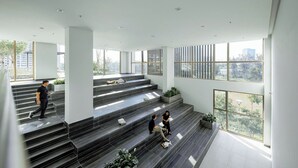 A spacious interior with a staircase leading to a balcony, large windows offering views of the city, and a modern design with minimalistic decor. - Luxury Apartment in Phu My Hung (Ho Chi Minh City)