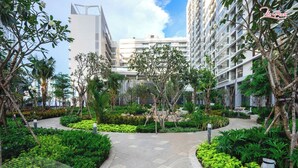 A modern urban courtyard with a central pathway, surrounded by lush greenery and tall buildings. - Luxury Apartment in Phu My Hung (Ho Chi Minh City)