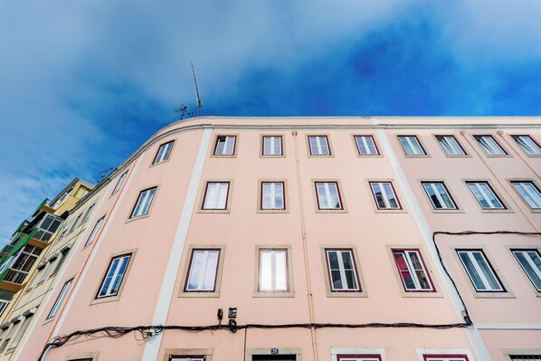 A multi-story building with a pink facade, multiple windows, and visible electrical wires.