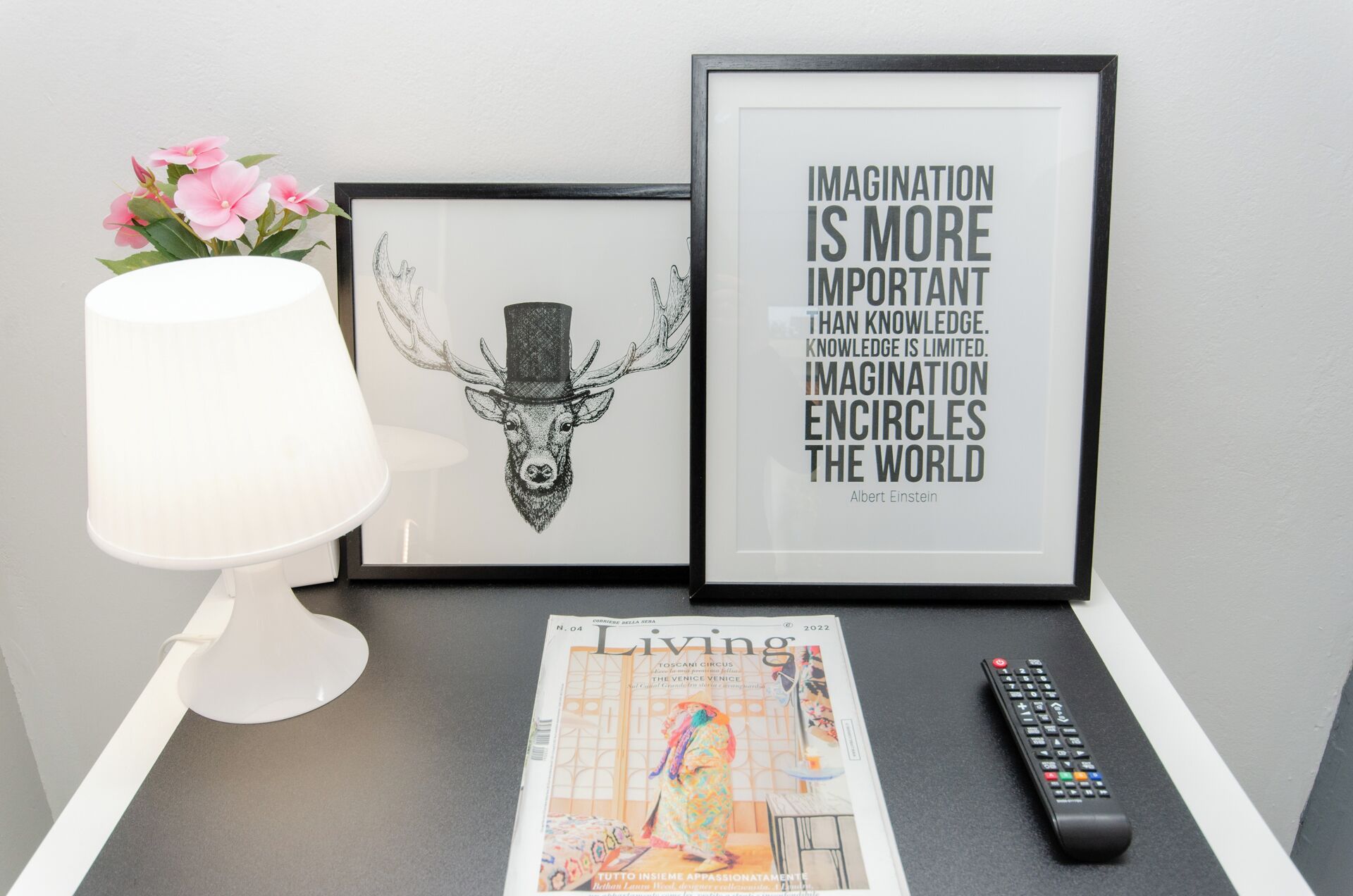 Une citation encadrée, un magazine, une télécommande et une lampe sur une table.