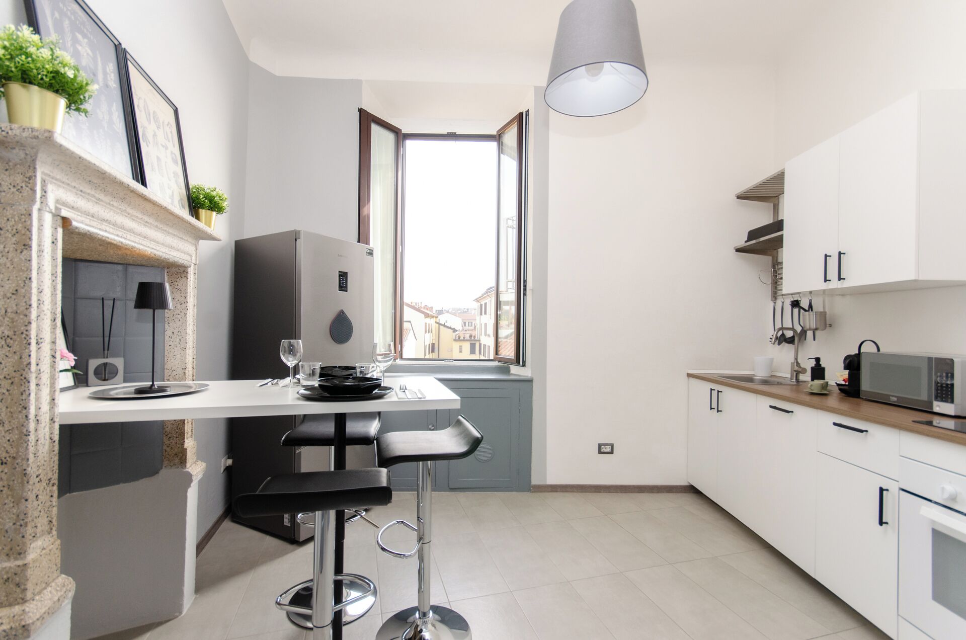 A modern kitchen with a built-in refrigerator, a dining area with a bar stool, and a window providing a view of the city.