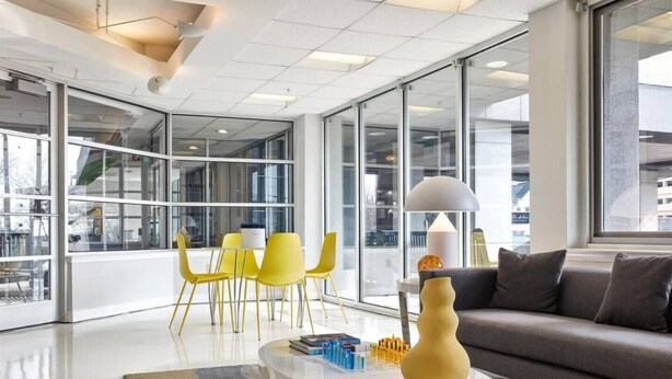 A modern interior with a glass wall, a sofa, yellow chairs, and a coffee table. - Cozy 1-bedroom condo with AC, WiFi in welcoming Towson (Towson)