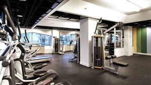 A modern gym with cardio machines, weightlifting equipment, and large windows offering views of the outdoors. - Cozy 1-bedroom condo with AC, WiFi in welcoming Towson (Towson)