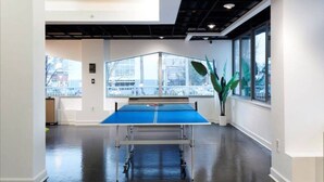 A ping pong table in a modern indoor space with large windows and a plant. - Cozy 1-bedroom condo with AC, WiFi in welcoming Towson (Towson)