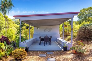 Relax in a serene outdoor space surrounded by lush greenery and plants, featuring a table, chairs, and a convenient sink.