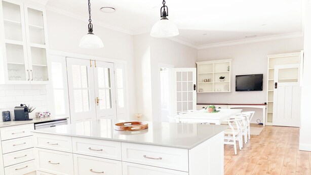 Una cocina moderna con armarios blancos, una isla grande e iluminación colgante.