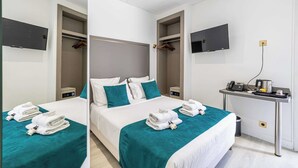 Ein Hotelzimmer mit Bett, Schreibtisch mit Telefon und Wasserkocher sowie einem an der Wand befestigten Fernseher.