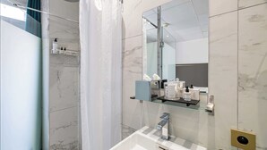 Ein modernes Badezimmer mit einer Duschkabine aus Glas, einem weißen Waschbecken und einem Spiegel darüber.