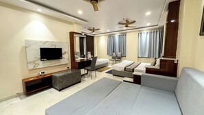 Una habitación de hotel moderna con una cama grande, un sofá, un escritorio y un televisor montado en la pared.